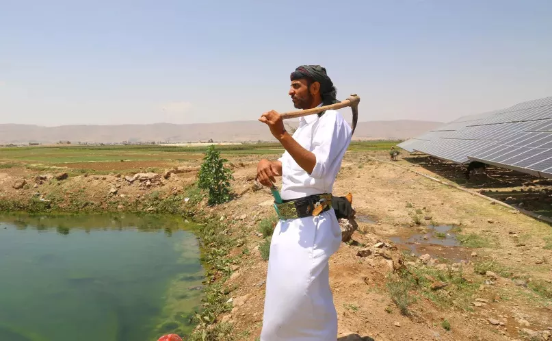 Un homme avec un outils contemple un champ au Moyen-Orient.