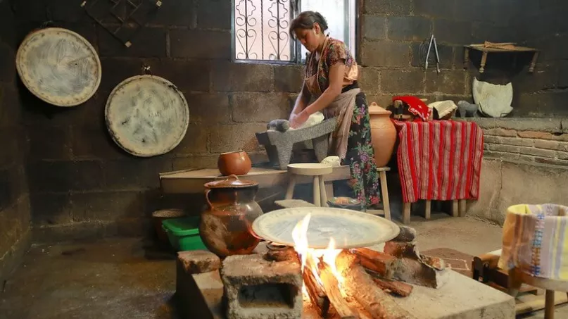 Una mujer parada amasando en una cocina en México.