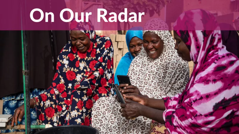 Four women look at a mobile phone together