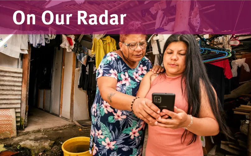 Two women stand together looking at a phone screen