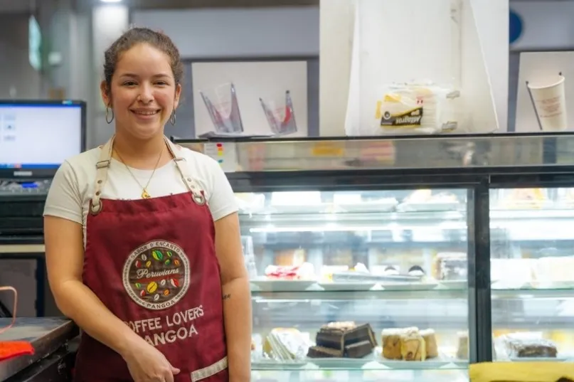 Jóven mujer frente a un mostrador de comidas en Colombia.