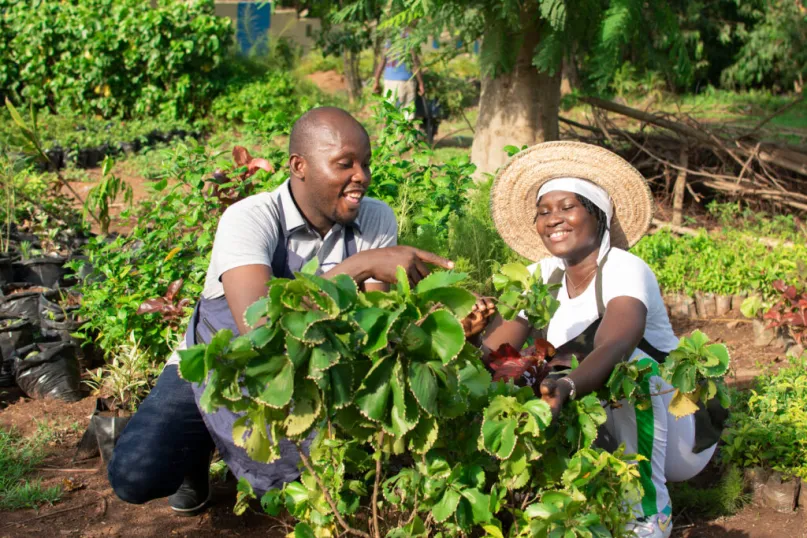 Two farmers looking at plants and smiling