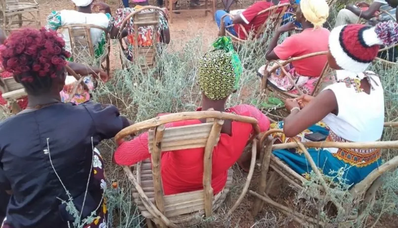 Women sitting on chairs in the open air.