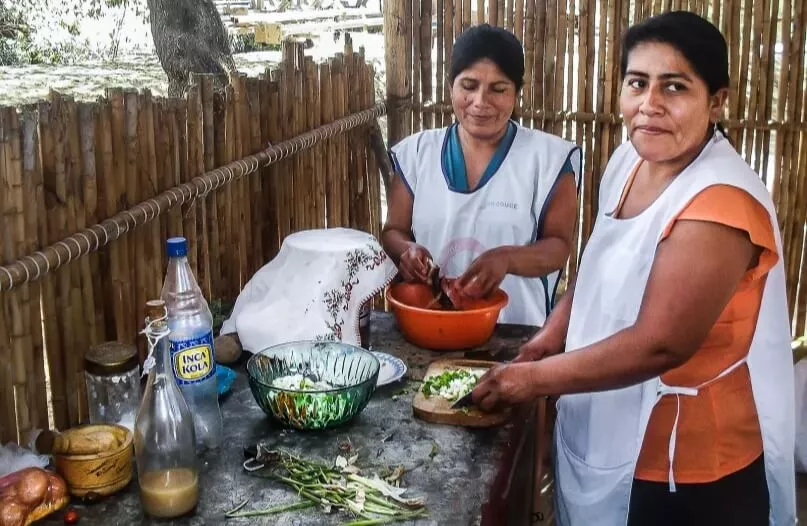 2 mujeres preparando ceviche ante una mesa con los ingredientes en Perú. 