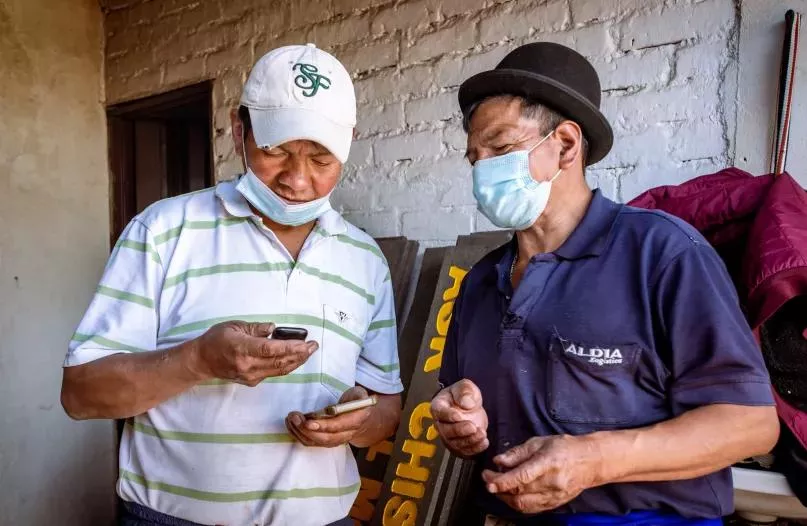 Dos hombres utilizando un teléfono celular en Colombia.