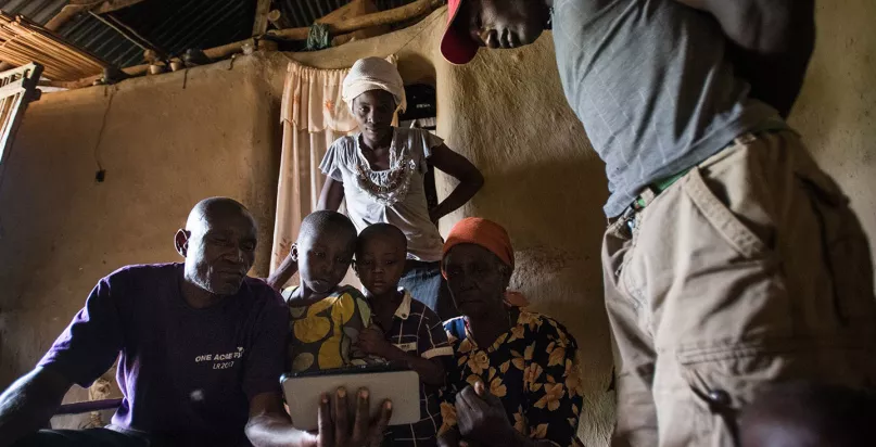 Un fermier kenyan et sa famille autour d'une tablette pour regarder une vidéo sur One Acre Fund. Photo de Hailey Tucker. Concours photos du CGAP 2017.