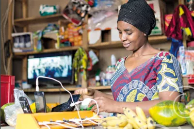 A store vendor looking at her mobile phone. GSMA Photo.