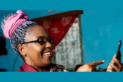 A woman pointing at her mobile device with a smile