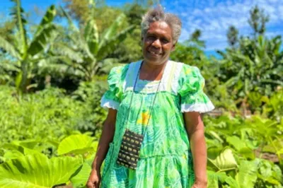 Woman in green dress standing in front of field of green plants.