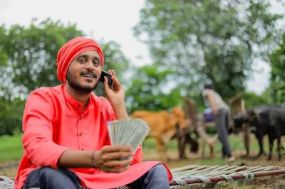 Man with red turban holding phone to ear and holding currency.