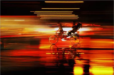 Blurry artistic photo of someone riding a bicycle with a child sitting in the back