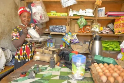 Une femme dans son magasin mesure de la farine avec une balance.