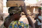 Woman holding savings group box on her head.