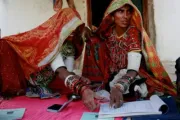 Two women signing on a journal with their thumb, India.