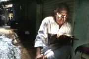 Man reading newspaper in alley. Photo by Rana Pandey, 2015 CGAP Photo Contest.