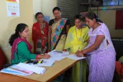 Women stand around a pile of papers