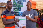 Two cocoa farmers holding up their document.