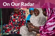 Four women look at a mobile phone together