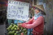 A fruit vendor smiles near her stand on the street