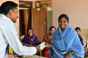 Woman at microfinance group meeting handing a paper to a man.